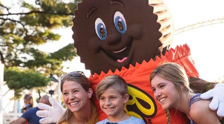 Life-sized Reese's Peanut Butter Cup character smiling for picture with children